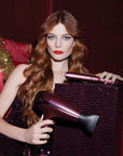 Model holding the ghd Deluxe Hairdryer & Straightener Gift Set in Cherry Chic