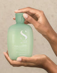 Model holding Alfaparf Milano Semi Di Lino Scalp Calming Micellar Low Shampoo