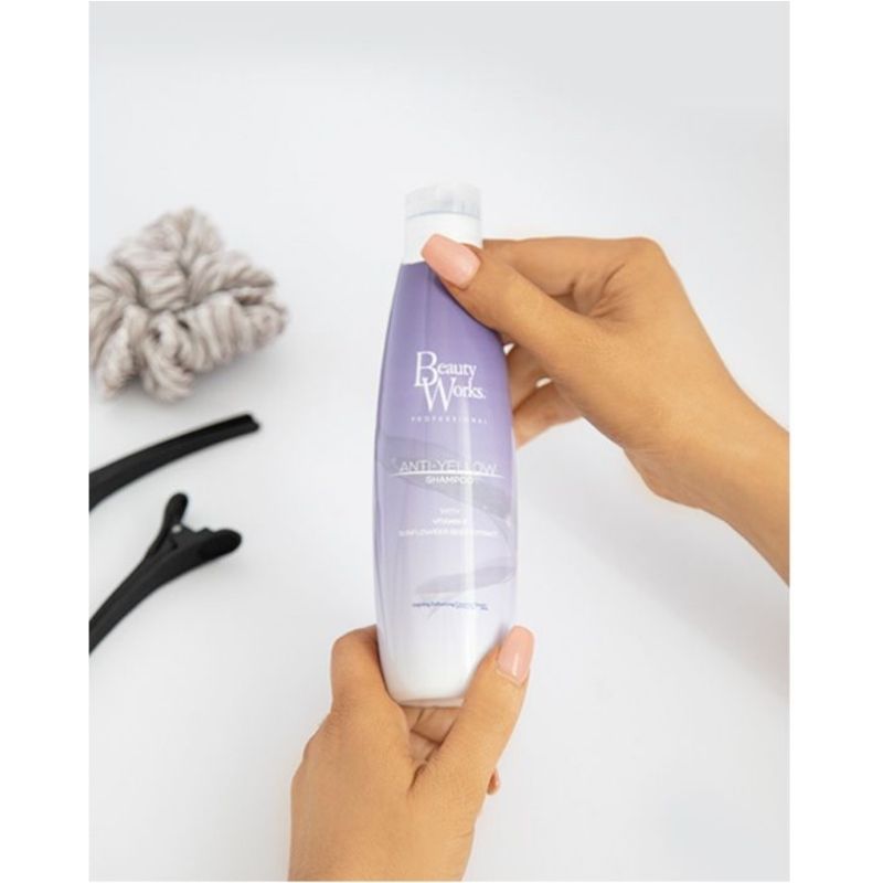 Model holding Beauty Works Anti Yellow Shampoo 