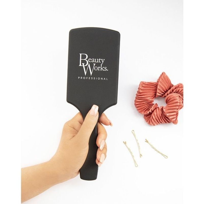 Model holding Beauty Works Large Paddle Brush