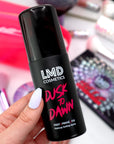 Model holding LMD Cosmetics Dusk To Dawn setting spray