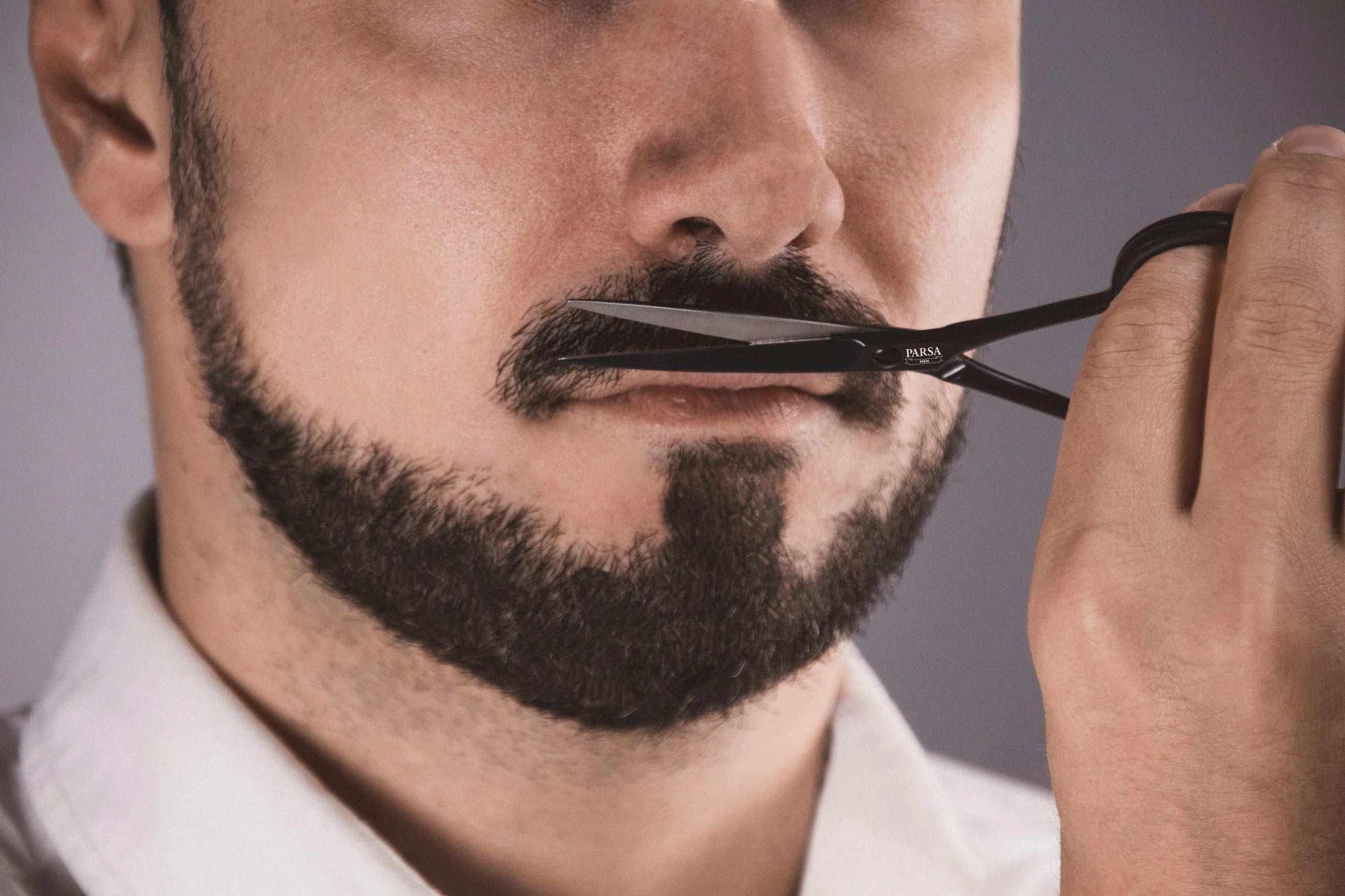 Model using Parsa Beauty Beard Grooming Set to trim beard