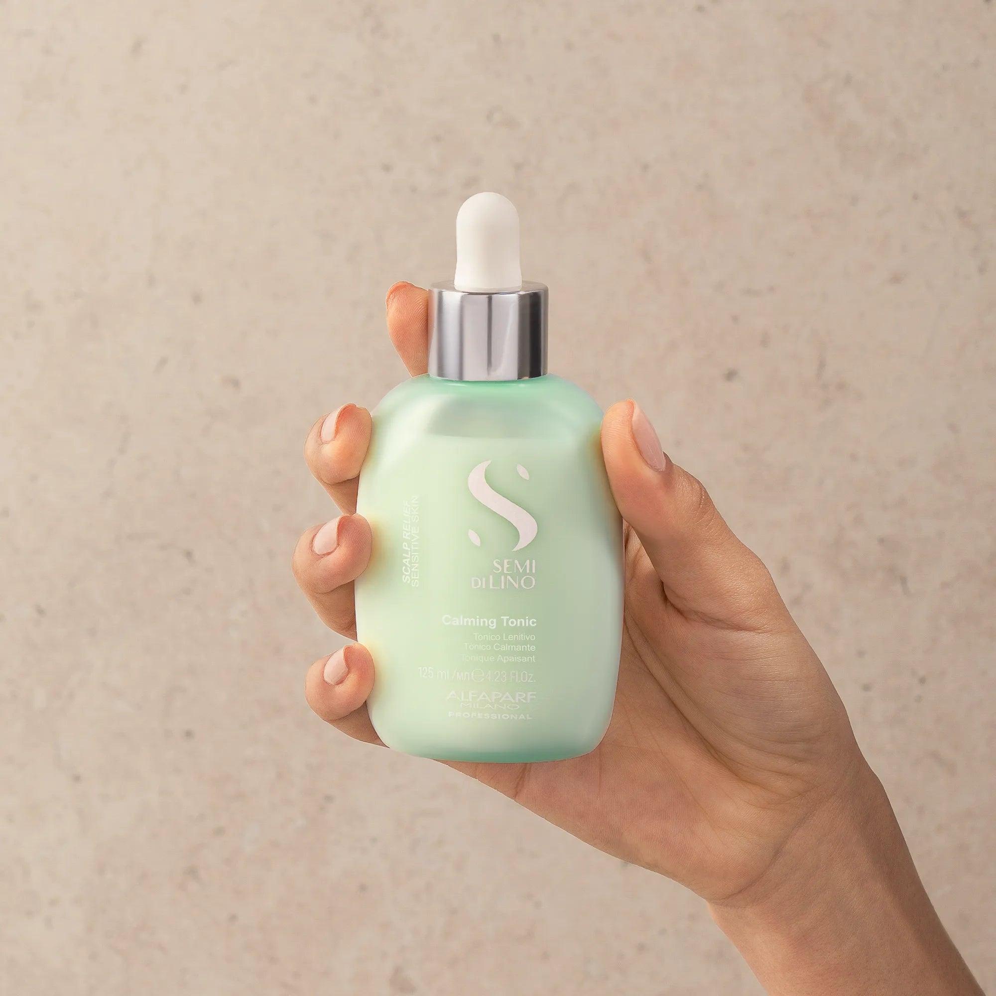 Model holding Alfaparf Milano Semi Di Lino Scalp Calming Tonic 125ml
