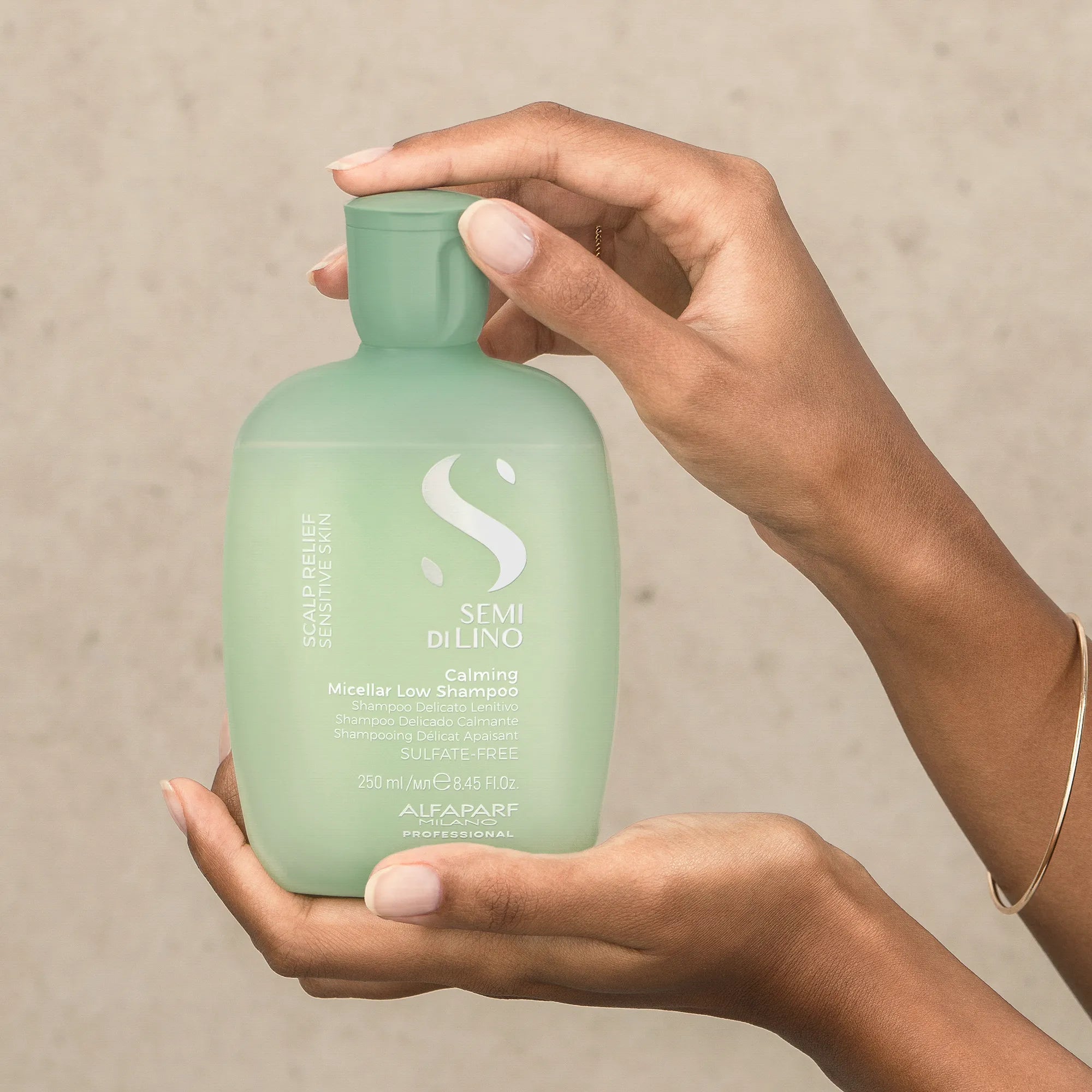 Model holding Alfaparf Milano Semi Di Lino Scalp Calming Micellar Low Shampoo 