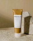 Skin1004 Centella Ampoule Foam sitting beside a stone