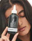 Model holding The INKEY List Caffeine Stimulating Scalp Treatment